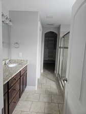 Full bath featuring vanity, a stall shower, light tile patterned floors, and a walk in closet
