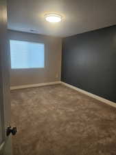 Unfurnished room featuring carpet flooring and a textured ceiling