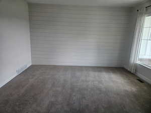 Carpeted spare room with baseboards and wood walls