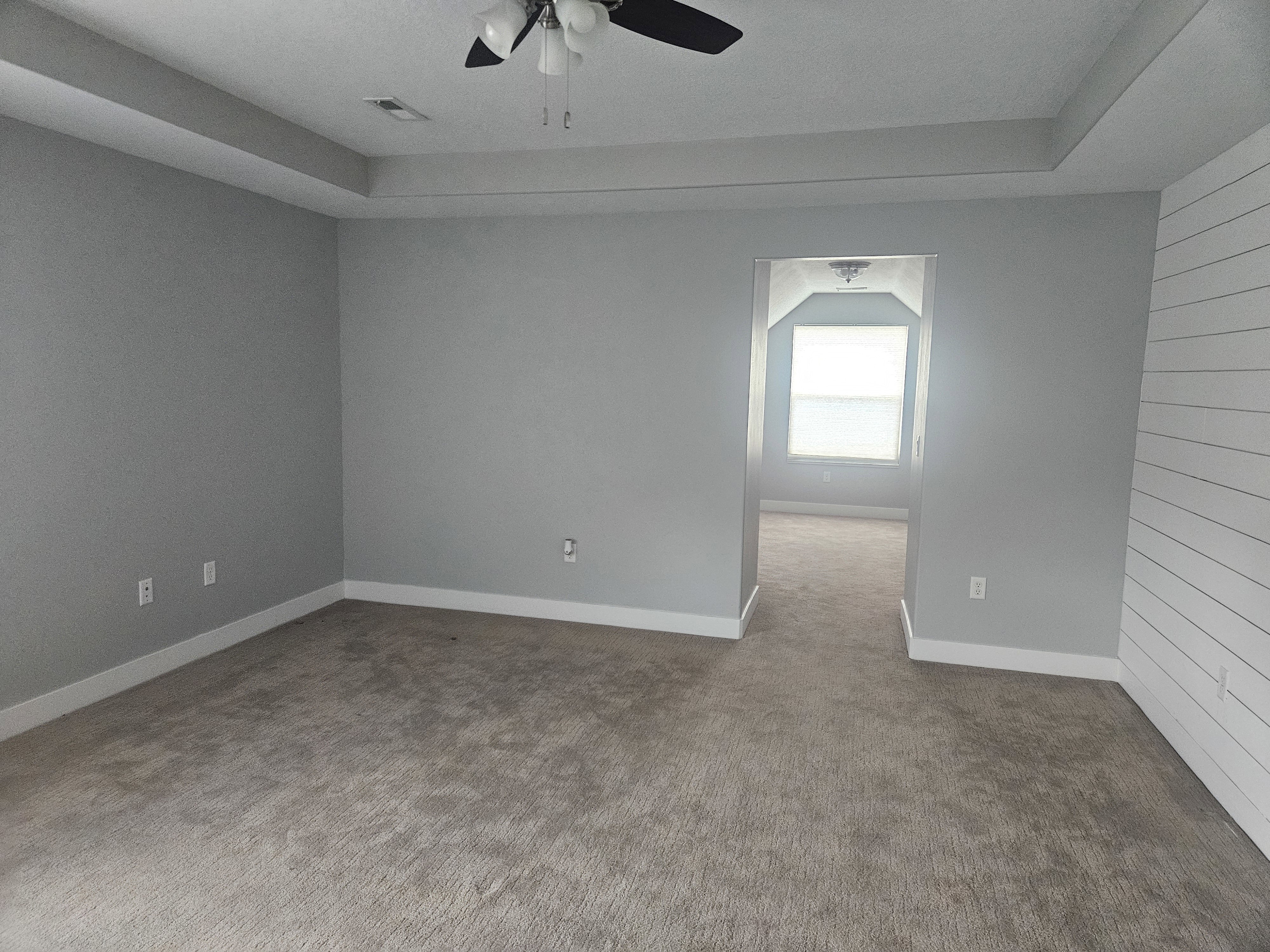 Carpeted spare room with baseboards and ceiling fan