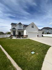 View of front of home featuring board and batten siding, driveway, roof mounted solar panels, and a garage