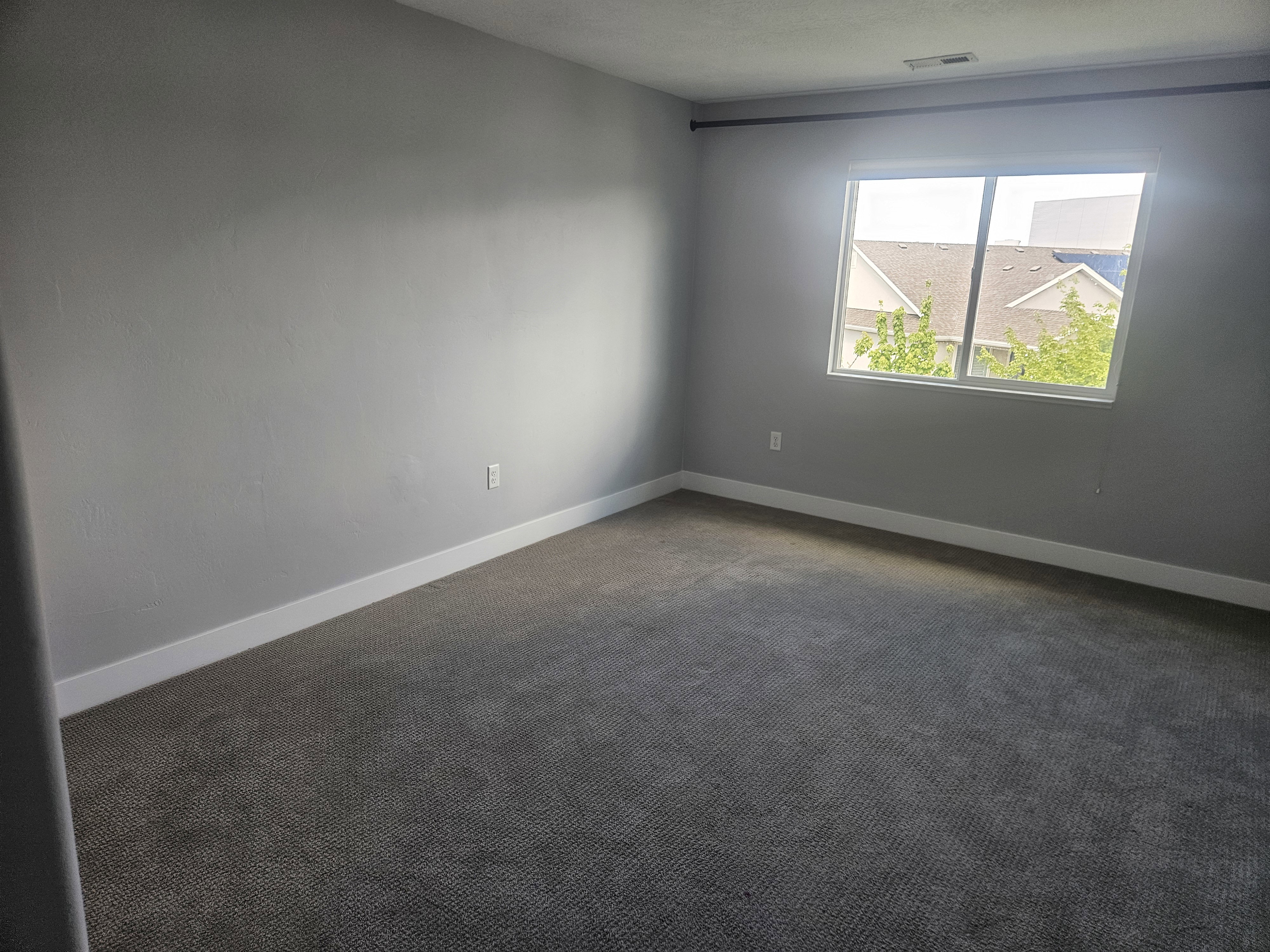 Spare room featuring dark carpet and baseboards