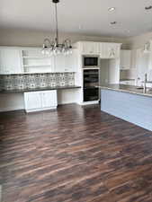 Kitchen featuring white cabinetry, suspended lighting, dark wood-style floors, and open shelves