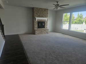Unfurnished living room with a fireplace, ceiling fan, and wooden walls