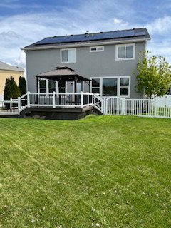 Rear view of property with a gazebo, solar panels, a deck, and stucco siding