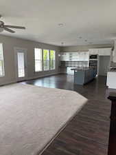 Living area featuring dark wood finished floors and a ceiling fan