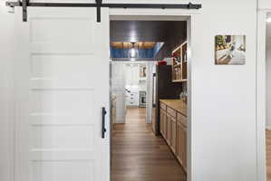 Kitchen featuring a barn door, dark wood-type flooring, stainless steel appliances, and butcher block counters