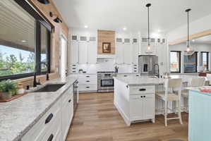 Kitchen featuring premium appliances, light stone counters, a breakfast bar, glass fronted cabinets, and backsplash