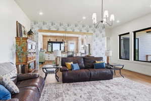 Living room featuring a chandelier, wallpapered walls, light wood-style flooring, and an accent wall