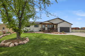 View of front of home featuring a porch, driveway, brick siding, and an attached garage