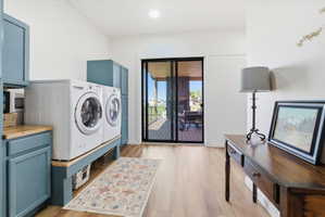 Laundry room featuring light wood finished floors, cabinet space, washing machine and clothes dryer, and recessed lighting
