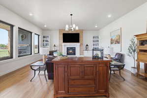 Living area with suspended lighting, light wood finished floors, and a large fireplace