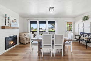 Dining room with light wood-style floors, a textured ceiling, and a glass covered fireplace