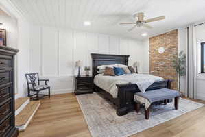 Bedroom featuring a decorative wall, light wood-style floors, ceiling fan, recessed lighting, and wood ceiling