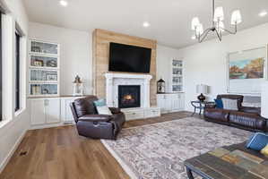Living area with dark wood finished floors, a fireplace, and a chandelier