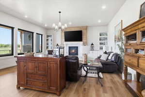 Living room with suspended lighting, light wood-style flooring, a glass covered fireplace, and built in shelves