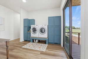 Laundry area with washer and dryer and light wood-style floors