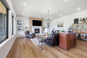 Living room featuring a large fireplace, hanging lights, and light wood finished floors