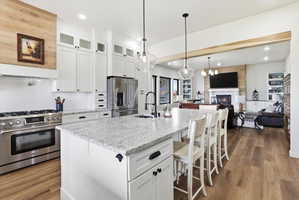 Kitchen featuring open floor plan, white cabinetry, high end appliances, a kitchen bar, and glass fronted cabinets