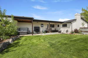 Back of property featuring a hot tub and a patio area