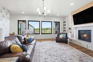Family room with a tiled fireplace, wood finished floors, and suspended lighting