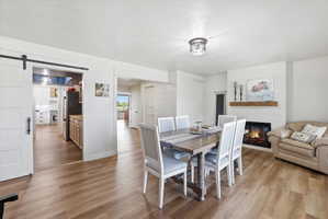 Dining area with a glass covered fireplace, light wood-style flooring, a barn door, and a textured ceiling