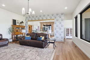 Living area with an accent wall, suspended lighting, light wood-style flooring, and wallpapered walls