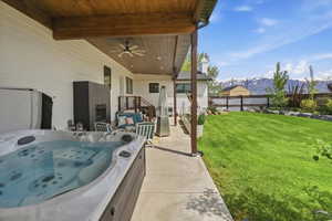 View of patio with a mountain view, a hot tub, and ceiling fan