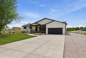 View of front of property featuring covered porch, concrete driveway, an attached garage, a storage shed, and brick siding