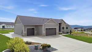 Craftsman-style home with board and batten siding, a garage, a front lawn, and concrete driveway