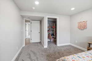 Bedroom featuring a walk in closet, light colored carpet, and recessed lighting