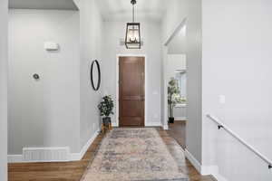 Foyer with dark wood-type flooring and hanging lights