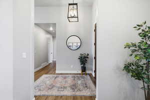 Foyer entrance with light wood-style flooring, a chandelier, and a high ceiling