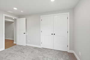 Unfurnished bedroom featuring light colored carpet, recessed lighting, and a closet