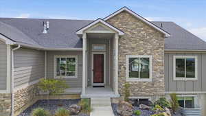 Property entrance featuring stone siding, a shingled roof, and board and batten siding