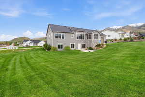 Rear view of property with a mountain view, a lawn, a patio, and a residential view