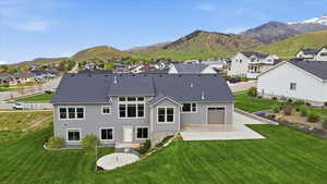 Back of house with a patio area, a mountain view, a residential view, and a lawn