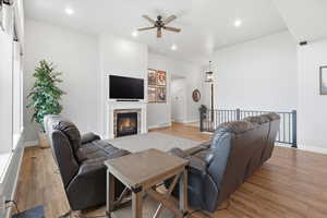 Living area featuring a ceiling fan, light wood-style flooring, recessed lighting, and a fireplace