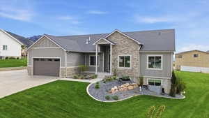 View of front of house with board and batten siding, stone siding, a front lawn, and an attached garage