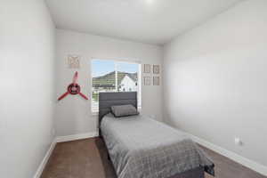 Bedroom featuring dark carpet and baseboards