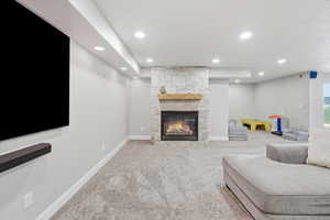 Living room with a stone fireplace, light colored carpet, and recessed lighting