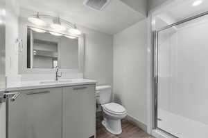 Full bathroom with vanity, a shower stall, light wood-style flooring, and a textured ceiling