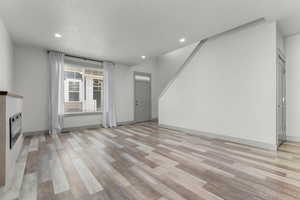 Unfurnished living room with a glass covered fireplace, light wood-style flooring, and recessed lighting