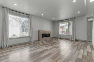 Unfurnished living room featuring recessed lighting, light wood finished floors, and a glass covered fireplace