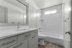 Bathroom featuring vanity, a textured ceiling, light wood-style flooring, and washtub / shower combination