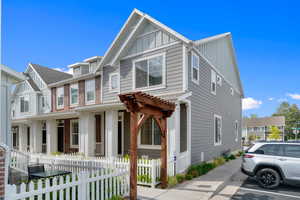 Craftsman inspired home with board and batten siding, a residential view, a fenced front yard, and brick siding