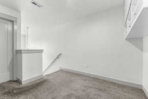 Carpeted empty room with baseboards and a textured ceiling