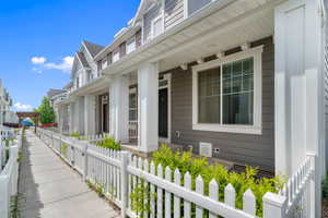View of side of property featuring a fenced front yard and covered porch