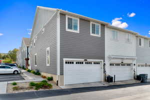 View of side of home featuring an attached garage and a cooling unit