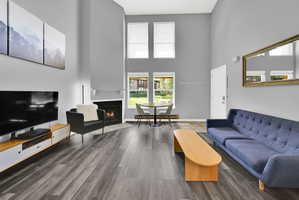 Lofted living room with upgraded, neutral LVP flooring, wood burning fireplace and modern finishes. New windows let in natural light.